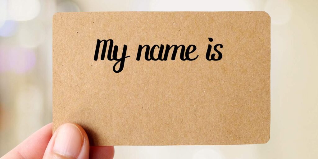 Imiona dla psa są ważne. Na zdjęciu dłoń trzymająca etykietę z plakietką "my name is.."